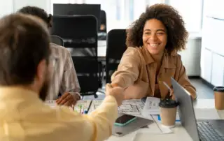 A woman at a desk shaking a man's hand